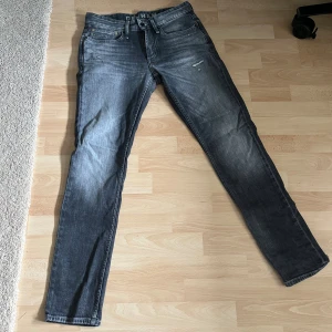 Denham Razor Slim Fit grå jeans - Snygga grå jeans från Denham i modellen Razor Slim Fit. Jeansen har en tvättad look med slitningar och klassiska fem fickor. De är tillverkade i bomull och har knappgylf. Perfekta för dig som gillar en smal passform och stilren design. 