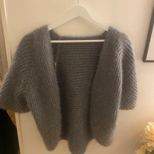 stickad kofta - Mysig och fluffig mörkgrå stickad kofta med breda ärmar och öppen front. Kommer inte ihåg vart ja köpte den men den är aldrig använd. Passar S-M 