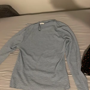 Ljusblå långärmad topp från Gina Tricot - Säljer en ljusblå långärmad topp från Gina Tricot. Toppen har en lätt skrynklig struktur och är i ett mjukt material som känns skönt mot huden. Perfekt att styla med jeans eller kjol för en chill look.