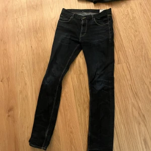 Mörkblå jeans från Emilio Denim - Snygga mörkblå jeans från Emilio Denim med klassisk femficksdesign och kontrastsömmar. Jeansen har en rak passform och är tillverkade i slitstarkt denimtyg. Perfekta för dig som gillar en stilren look med tydliga detaljer och bekväm känsla.