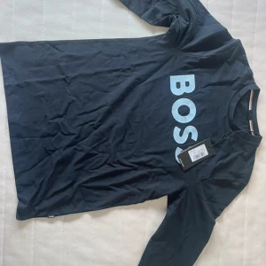 Mörkblå långärmad t-shirt från Hugo BOSS - Snygg mörkblå långärmad t-shirt från BOSS med stor ljusblå logga framtill. Helt oanvänd med prislapp kvar. 