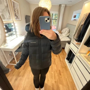 Svart pufferjacka från Peak Performance - Säljer en svart pufferjacka från Peak Performance med huva och dragkedja framtill. Jackan är vadderad och har en clean, oversized look som är perfekt för kalla dagar. Klassisk Peak-logga på bröstet och skön passform. Grym jacka för vintern! Använd en vinter men ör som nytt skick. Säljer även en lika dan i S. 