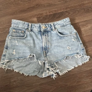 Ljusa jeansshorts från Pull&Bear - Säljer ett par ljusblå jeansshorts från Pull&Bear i storlek 36. Medel höga i midjan med råa och fransiga kanter samt slitna detaljer på framsidan. Perferka till sommaren💕