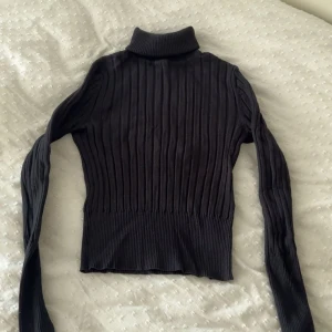 Svart ribbad polotröja från Zara - Svart ribbad polotröja från Zara i storlek S. Tröjan har lång ärm, hög polokrage och är figurnära med stretchigt material. Perfekt för lager-på-lager och enkel att styla till olika outfits.