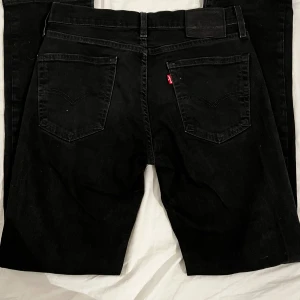 Levi's 511 svarta jeans - Svarta Levi's 511 jeans med klassisk femficksdesign och smal passform. Jeansen har svarta sömmar, Levi's logga på bakfickan och svart läderpatch i midjan. Tillverkade i bomull med en snygg, stilren look.