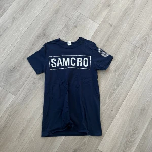 Mörkblå Sons of Anarchy t-shirt Gildan - Mörkblå t-shirt från Gildan med stort vitt SAMCRO-tryck på bröstet och Sons of Anarchy-logga på ärmen. Klassisk passform, rund hals och tillverkad i mjuk bomull. Perfekt för dig som vill ha en snygg statement-tee. Tar gärna fler bilder, mått och svarar på frågor!💙