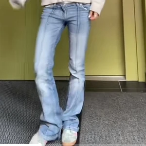Blå bootcut jeans med pressveck - Snygga ljusblå bootcut jeans med markerade pressveck längs benen. Lågmidja och klassisk femficksdesign. Jeansen har en lätt tvättad look och är tillverkade i stretchig denim för en bekväm passform. Lite sönder längst ner på benen! (Pris kan diskuteras!)