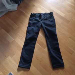 Svarta Replay Anbass jeans - Säljer ett par svarta Replay Anbass jeans med klassisk femficksdesign och raka ben. Jeansen är handgjorda i Italien och har en stilren look med mörk tvätt. Perfekta för dig som gillar en clean och tidlös stil waist 29 length 34