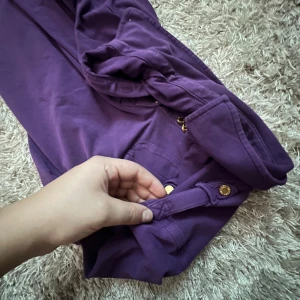 Tommy Hilfiger Tröja - Säljer nu en jättefin Tommy Hilfiger tröja med guldiga detaljer och fickor på brösten. Jättecool tröja i lila i mycket bra skick. Skriv vid frågor!💕