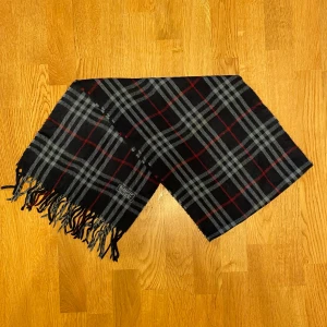 Mörkblå Burberry halsduk i kashmir - Säljer en mörkblå Burberry halsduk i kashmir tyg. Halsduken är gjord i 100% kashmir. Den är i gott skick. Var inte rädd för frågor.