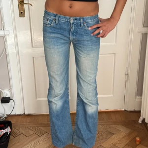 Replay ljusblå bootcut jeans - Ljusblå replay jeans med bootcut passform och klassisk femficksdesign. Jeansen har låg midja och är tillverkade i mjukt denim med snyggt slitna detaljer framtill och baktill. Perfekta för en avslappnad och trendig look. Har igensydda hål som syns på sista bilden (det är lappat och inte längre ett hål men något som syns)