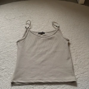 Beige ribbad linnetopp från Hostess - Säljer en beige ribbad linnetopp från Hostess med smala axelband i silverfärgad metall. Aldrig använd, passar XXS/XS/S 🤎