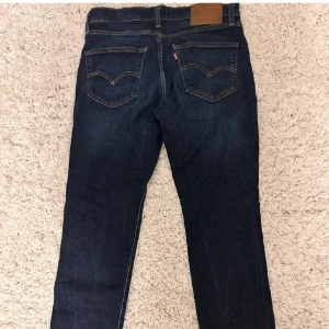 Levi's 511 mörkblå jeans W32 L30 - Snygga Levi's 511 jeans i mörkblå tvätt med klassiska fem fickor och orange sömmar. Modellen är slim och har raka ben, tillverkade i mjukt jeanstyg. Perfekta för dig som gillar en stilren och tidlös look.