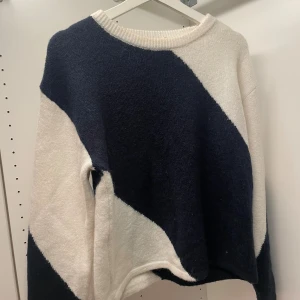 Randig stickad tröja från Gina Tricot - Säljer en stickad tröja från Gina Tricot med breda diagonala ränder i mörkblått och vitt. Tröjan har rund halsringning och långa ärmar. Perfekt för dig som gillar en chill och snygg stil.