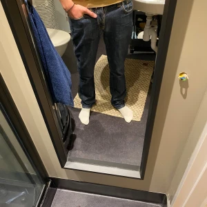 Blå jeans från Nudie Jeans Co - Snygga blå jeans från Nudie Jeans Co med klassisk orange söm och logga på bakfickan. Jeansen har rak passform, normal midja och är tillverkade i slitstarkt bomullsdenim. Perfekta för dig som gillar en tidlös och clean look. Strl 30/34