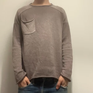 Beige stickad tröja med bröstficka - Säljer en beige stickad tröja med rund halsringning och en snygg bröstficka på vänster sida, Modellen är 180 och väger 70kg.