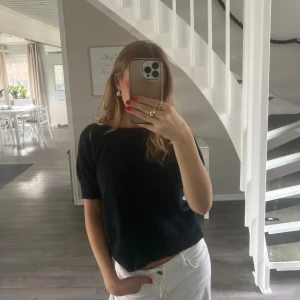 Svart, kortärmad stickad tröja  - En svart kortärmad stickad tröja