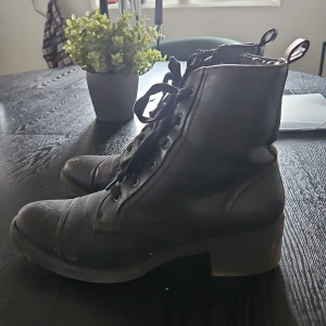 Svarta kängor med snörning - Svarta kängor i skinn med snörning, lätt fodrade och rund tå. De har en stadig klack och dragflik baktill för enkel påtagning. Perfekta för dig som gillar en tuff och stilren look till vardags.