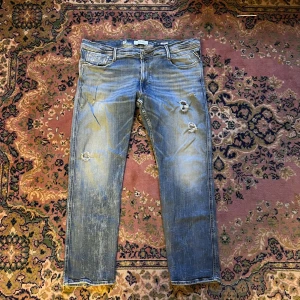 Replay Anbass ljusblå slitna jeans 44/32 5 years aged - Säljer ett par Replay Anbass jeans i ljusblå tvätt med slitningar och hål på benen för en riktigt avslappnad vibe. Klassisk femficksmodell, normal passform och tillverkade i mjukt denim. Perfekta för dig som gillar en streetig look.