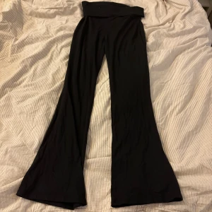 Svarta bootcut byxor från Gina Tricot - Svarta bootcut byxor från Gina Tricot med hög midja och mjukt, stretchigt material. Byxorna har en snygg utsvängd passform och är perfekta för en trendig och bekväm look. Passar dig som gillar stilrena och enkla plagg.