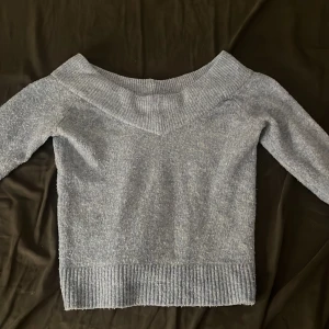 Blå offshoulder stickad tröja H&M XS - Mysig blå stickad tröja från H&M i storlek XS. Tröjan har en bred ribbad kant och offshoulder-modell som ger en snygg och avslappnad vibe. Perfekt för kyliga dagar när du vill vara både bekväm och stilren.