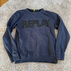 Mörkblå sweatshirt från Replay - Säljer en mörkblå sweatshirt från Replay med stor svart logotyp framtill. Tröjan har rund halsringning, långa ärmar och ribbade muddar vid ärmslut och nederkant. Perfekt för dig som gillar en enkel men snygg streetstil.