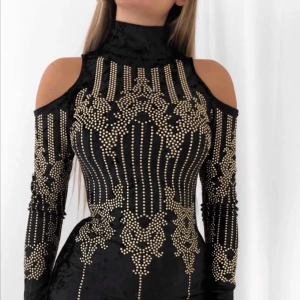 Svart sammetsklänning med guldmönster nyår nyårsklänning fest - DM ”viva dress”. Supersnygg svart sammetsklänning med tight passform och coola cut out-detaljer vid axlarna. Klänningen har långa ärmar och är täckt av glittriga guldfärgade nitar i ett unikt mönster. Perfekt för dig som vill sticka ut och glänsa.