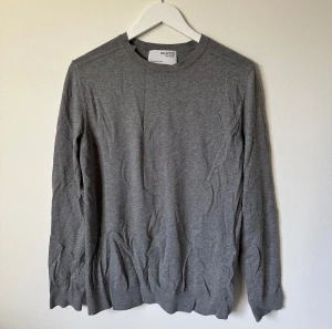 Grå bomullströja från Selected Homme - En stilren grå tröja från Selected Homme i 100% bomull. Klassisk rund hals och långärmad modell med ribbade muddar vid ärmslut och nederkant. Perfekt för dig som gillar enkel och clean look. Passar dig som vill ha en normal passform. 4Ö19