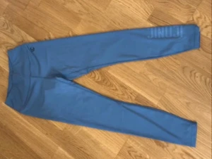 Blå Iconic leggings XS - Snygga blå leggings från Iconic i storlek XS. Tillverkade av 80% polyester och 20% elastan för en stretchig och bekväm passform. Diskret logga på höften och trycket 'ICONIC' längs benet. Perfekta för träning eller chill.