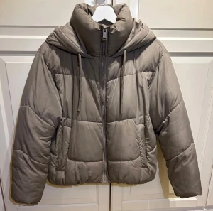 Beige pufferjacka från Zara - Säljer en snygg beige pufferjacka från Zara. Den har en dragkedja framtill och en mysig huva. Perfekt för kyliga dagar med sin quiltade design. Jackan är i mycket bra skick och passar perfekt till vintern! Säljer den nu för 250!