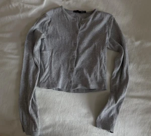 Grå ribbad croppad kofta  - Ribbad tunn kofta/topp och rund hals, har långa ärmar och knappar framtill, jätteskön!! 💕