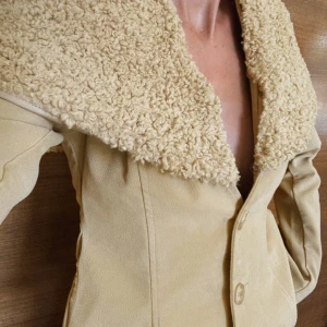 Nakd teddyjacka / suede mocka jacka kappa päls - Går att ta av kragen för annan look! Snygg beige teddyjacka med bred, fluffig krage i teddy-material. Jackan har figurnära passform, två knappar framtill och långa ärmar. Perfekt för dig som vill ha en unik och trendig look med extra cozy vibes. Från Lovisa Worges kollektion endast testad! I storlek 32 men jag är en s. 