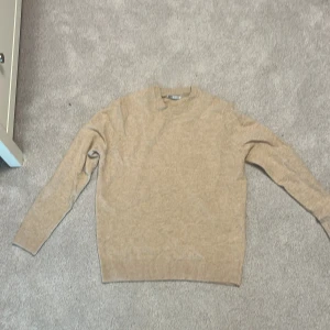 Beige stickad tröja från Zara - En stilren beige stickad tröja från Zara . Tröjan har rund halsringning, ribbade muddar och är långärmad. Perfekt för lager-på-lager och enkel att matcha med olika outfits. Väldigt bekväm tröja