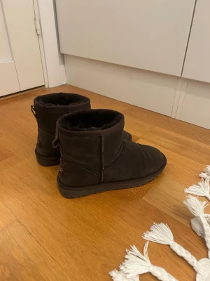 Mörkbruna boots i mocka 38 1/2 eller 39 - Klassiska mörkbruna vinterboots i mjuk mocka med rund tå och platt sula. Insidan är fodrad med fluffig päls för extra värme. Perfekta för kyliga dagar och enkel att matcha med olika outfits.