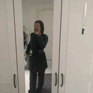 Svart rock med skinnärmar och dragkedja - Denna tunna jackan hade jag sagt passar för dessutom strl s. Den har snygga skinnärmar och coola dragkedjedetaljer vid fickorna. Jackan har en rak och längre passform som ger en stilren vibe. Perfekt för dig som gillar en mörk och edgy look med lite extra attityd.