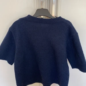Mörkblå stickad tröja från Kappahl - Mysig mörkblå stickad tröja från Kappahl i storlek 158/164. Tröjan har korta ärmar.