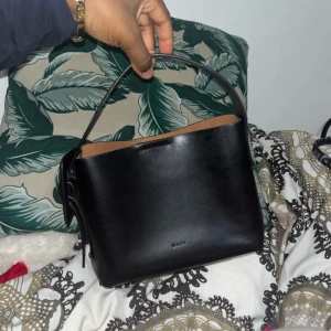 Svart handväska i skinn från Åhléns  - Handväska använt 2 gånger. Den är i ett jätte bra stick. Köpte den för 1 199 på Åhléns     PRIS!! 49.96% rabatt passa på köp först!!!