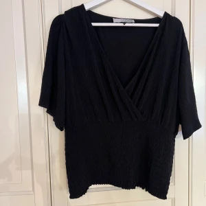 Svart omlottopp  - Säljer en svart omlottopp från Visual clothing project, köpt på MQ.