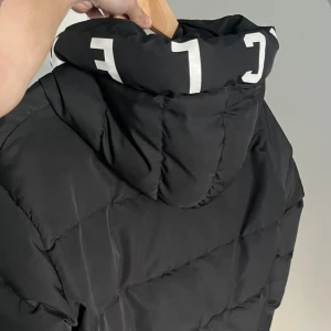 Svart Moncler pufferjacka  - Svart pufferjacka från Moncler med stor huva och vit logotyptext. Helt ny (oanvänd). Skriv vid funderingar! S