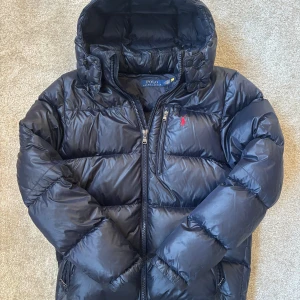 Ralph Lauren jacka  - Tja säljer nu en vinterjacka från Polo Ralph Lauren då den inte kommer till användning längre. Storlek M och en glossy mörkblå färg. Endast använd fåtal gånger och inga skador eller liknande. Hör av er om ni har några frågor eller funderingar!