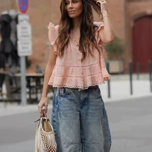 Ljusrosa volangblus med spetsdetaljer - Supersöt ljusrosa blus med volanger och spetsdetaljer. Blusen har v-ringning, knappar framtill och korta ärmar med volang. Den är luftig och har en romantisk känsla, perfekt till jeans eller kjol.
