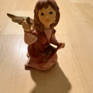 Goebel Ängel Figur - Vacker Goebel ängel i keramik, handmålad med fina detaljer och stjärnor på klänningen. Märkt undertill. Bra skick, inga synliga sprickor eller större skador. Perfekt för samlare eller som dekoration.