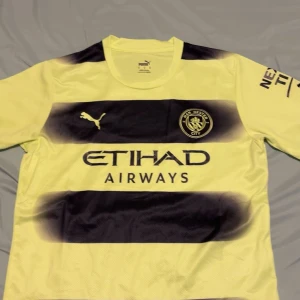 Manchester City gul och svart matchtröja M  - Säljer en Manchester City fotbollströja från Puma i gul och svart med breda horisontella ränder. Tröjan har korta ärmar, rund hals och klubbmärke på bröstet. Materialet är lätt och andas, perfekt för träning eller match. Etihad Airways-logga på framsidan. priset kan diskuteras