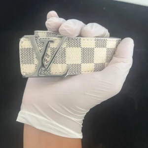 Beigt bälte med silver spänne - Beigt bälte med bokstäverna L och V i silver, med låda