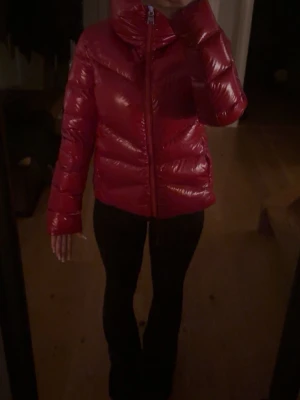 Röd glansig dunjacka från colmar - Snygg röd dunjacka från Colmar med glansig finish och hög krage.  Jackan har använts 1 gång och priset kan diskuteras Jackan har quiltad design, dragkedja framtill och Colmar logga på ärmen. Perfekt för kalla dagar och ger en trendig look.