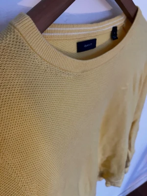 Gul stickad tröja från GANT - Snygg gul stickad tröja från GANT med rund halsringning och diskret strukturstickning. Tröjan har en avslappnad passform och är perfekt för dig som vill ha en färgklick i garderoben. Materialet känns mjukt och andas bra.