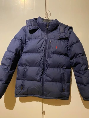 Blå dunjacka från Polo Ralph Lauren (170cm - Säljer en snygg Ralph Lauren jacka i storlek 170 men sitter som S. jackan är från kidsbrandstore och nypris är 3300kr, mitt pris 2000kr. kan gå ner vid pris vid snabbare affär