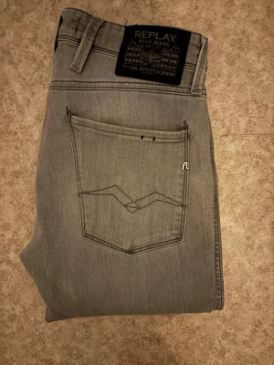 Grå Replay jeans anbass slim fit - Snygga grå jeans från Replay med klassisk femficksdesign med passformen slim fit. Jeansen har diskreta sömmar på bakfickorna och svart Replay-lapp i midjan. Perfekta för dig som gillar stilrena och tidlösa jeans. För fler bilder eller frågor är det bara att skriva.knappt använda så i ett bra skick