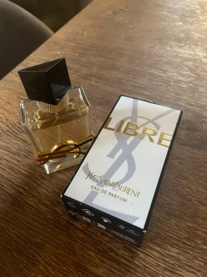 Yves Saint Laurent Libre Parfym - En lyxig parfym från Yves Saint Laurent med elegant glasflaska, guldiga detaljer och svart lock. Doften är Eau de Parfum och flaskan har en modern, stilren design med YSL-loggan i guld runt flaskan. Kolla bild hur mycket är kvar😊 Supergooood men har för många andra😊 Köpt ca 1500kr. Använd gärna köp nu❤️ 