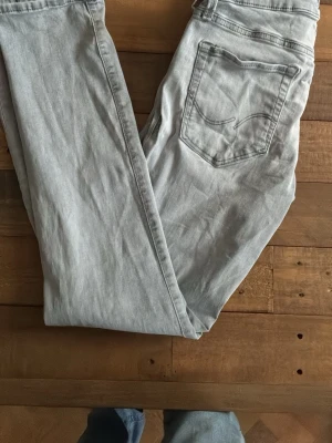 Ljusgrå jeans från Nudie Jeans - Säljer ett par ljusgråa jeans från Jack mad Jones Jeans med klassisk femficksdesign och snygga sömmar på bakfickorna. Jeansen har rak passform och är tillverkade i mjukt denimtyg. Perfekta för en avslappnad och stilren look.